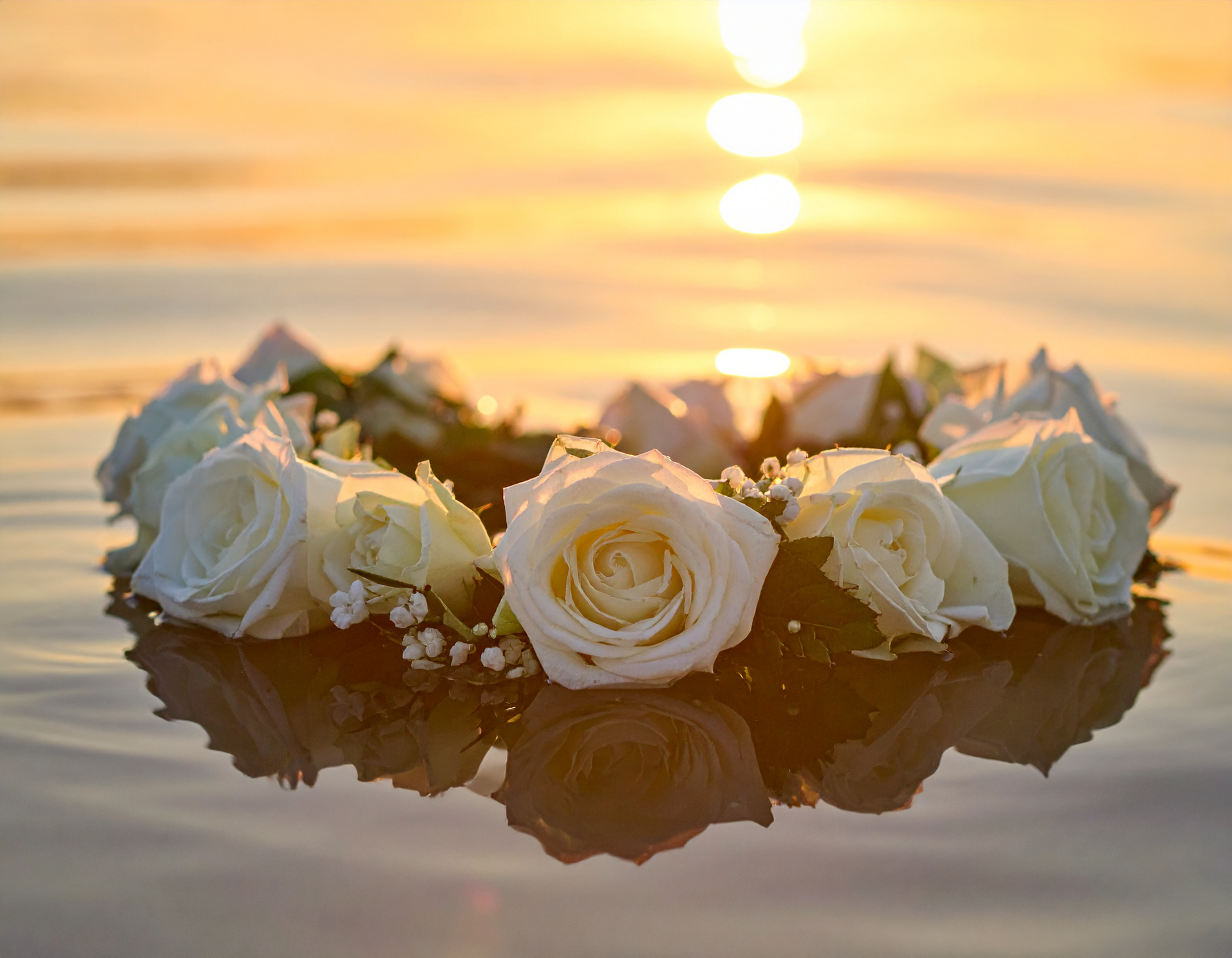 Blumenkranz auf seichtem Wasser als Sinnbild für Seebestattungen