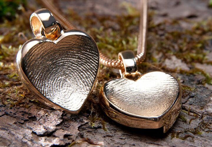 Nahaufnahme einer Kette mit Herzanhänger und Fingerabdruck als Erinnerungsschmuck